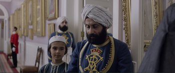 Movie still from “Victoria & Abdul” (2017), directed by Stephen Frears – A man and a boy dressed in blue and white; Medium shot, Low angle
