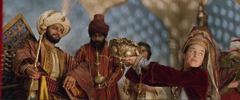 Movie still from “Victoria & Abdul” (2017), directed by Stephen Frears – A man in a turban is holding a gold crown; Medium shot, Over the shoulder angle