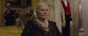 Movie still from “Victoria & Abdul” (2017), directed by Stephen Frears – An older woman wearing a crown and a dress; Close Up shot, Over the shoulder angle