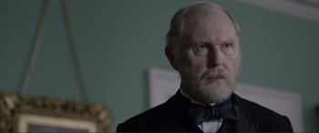 Movie still from “Victoria & Abdul” (2017), directed by Stephen Frears – An old man with a beard wearing a suit and bow tie; Close Up shot, Over the shoulder angle