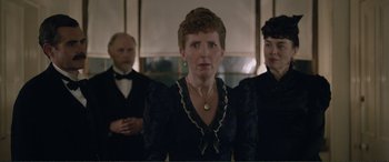 Movie still from “Victoria & Abdul” (2017), directed by Stephen Frears – A woman standing in front of two other people; Medium shot, Over the shoulder angle