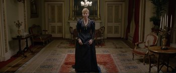 Movie still from “Victoria & Abdul” (2017), directed by Stephen Frears – A woman in a black dress standing in front of a painting; Wide shot, Low angle