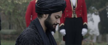 Movie still from “Victoria & Abdul” (2017), directed by Stephen Frears – A man with a turban is standing in front of two men in suits; Close Up shot, Over the shoulder angle