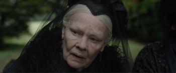 Movie still from “Victoria & Abdul” (2017), directed by Stephen Frears – An older woman wearing a black hat and holding an umbrella; Close Up shot, Over the shoulder angle