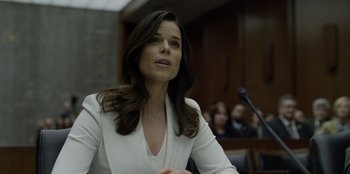 Movie still from “House of Cards” (2013), created by Beau Willimon – A woman in a white jacket is sitting in front of a microphone; Close Up shot, Over the shoulder angle