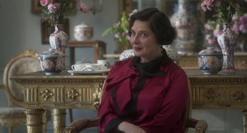 Movie still from “Vita & Virginia” (2018), directed by Chanya Button – An older woman sitting in a chair in a room; Close Up shot, Over the shoulder angle