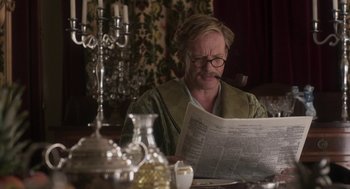 Movie still from “Vita & Virginia” (2018), directed by Chanya Button – An older man sitting at a table reading a newspaper; Medium shot, Over the shoulder angle