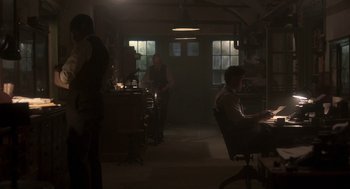 Movie still from “Vita & Virginia” (2018), directed by Chanya Button – A man sitting at a table in a dark room; Wide shot, Low angle