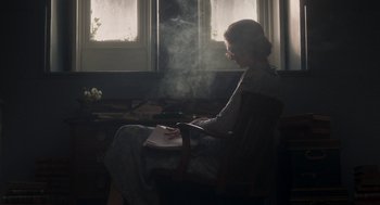 Movie still from “Vita & Virginia” (2018), directed by Chanya Button – A woman sitting in a chair writing in a notebook; Medium shot, High angle