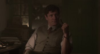 Movie still from “Vita & Virginia” (2018), directed by Chanya Button – A man sitting in a chair holding a pen in his hand; Close Up shot, Over the shoulder angle