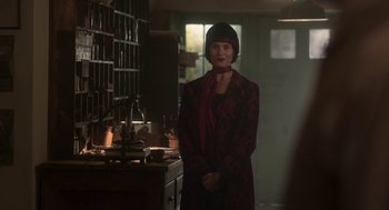 Movie still from “Vita & Virginia” (2018), directed by Chanya Button – A woman standing in front of a table in a room; Medium shot, Over the shoulder angle
