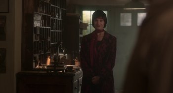 Movie still from “Vita & Virginia” (2018), directed by Chanya Button – A woman standing in front of a counter in a room; Medium shot, Over the shoulder angle