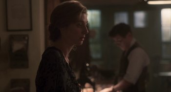 Movie still from “Vita & Virginia” (2018), directed by Chanya Button – A woman in a black dress is standing next to a man in a brown suit; Close Up shot, Over the shoulder angle