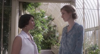 Movie still from “Vita & Virginia” (2018), directed by Chanya Button – Two women standing next to each other in front of plants; Medium shot, Over the shoulder angle