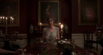 Movie still from “Vita & Virginia” (2018), directed by Chanya Button – A woman sitting at a dinner table in front of a painting; Medium shot, Over the shoulder angle