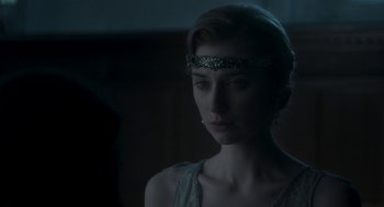 Movie still from “Vita & Virginia” (2018), directed by Chanya Button – A woman wearing a head piece in a dark room; Close Up shot, Over the shoulder angle
