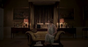 Movie still from “Vita & Virginia” (2018), directed by Chanya Button – A woman sitting on top of a couch in a living room; Wide shot, High angle
