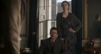 Movie still from “Vita & Virginia” (2018), directed by Chanya Button – A man and a woman standing next to each other in front of a window; Medium shot, Low angle