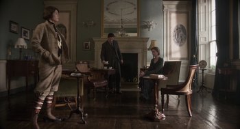 Movie still from “Vita & Virginia” (2018), directed by Chanya Button – A group of people sitting in a living room next to a fire place; Wide shot, Low angle