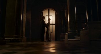 Movie still from “Vita & Virginia” (2018), directed by Chanya Button – A man and a woman standing in front of an open door; Wide shot, Low angle