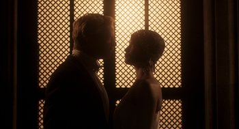 Movie still from “Vita & Virginia” (2018), directed by Chanya Button – A man and a woman standing next to each other in front of a window; Medium shot, Low angle