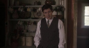 Movie still from “Vita & Virginia” (2018), directed by Chanya Button – A man standing in front of a wall of dishes; Medium shot, Over the shoulder angle