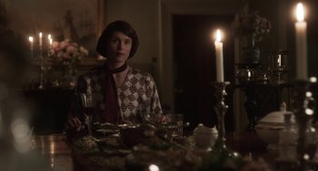 Movie still from “Vita & Virginia” (2018), directed by Chanya Button – A woman sitting at a dinner table with a glass of wine; Medium shot, Over the shoulder angle
