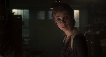 Movie still from “Vita & Virginia” (2018), directed by Chanya Button – A woman wearing glasses standing in a dark room; Close Up shot, Over the shoulder angle