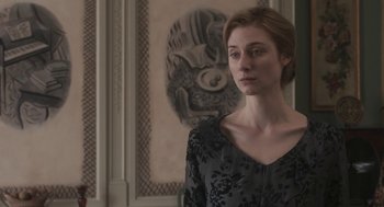 Movie still from “Vita & Virginia” (2018), directed by Chanya Button – A woman standing in front of a wall with a painting; Medium shot, Over the shoulder angle
