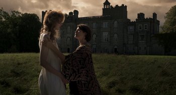 Movie still from “Vita & Virginia” (2018), directed by Chanya Button – Two women standing next to each other in front of a castle; Medium shot, Low angle
