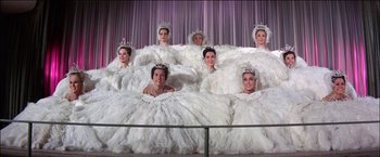 Movie still from “Viva Las Vegas” (1964), directed by George Sidney – A group of women dressed in white gowns and tiaras; Wide shot, Low angle