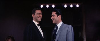 Movie still from “Viva Las Vegas” (1964), directed by George Sidney – A couple of men standing next to each other; Medium shot, Low angle