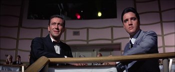 Movie still from “Viva Las Vegas” (1964), directed by George Sidney – A man in a tuxedo sitting at a table; Medium shot, Low angle
