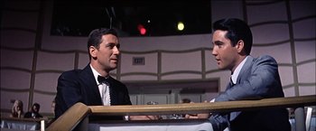 Movie still from “Viva Las Vegas” (1964), directed by George Sidney – Two men are sitting at a table and talking to each other; Medium shot, Low angle