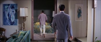 Movie still from “Viva Las Vegas” (1964), directed by George Sidney – A man in a suit and a man in a striped shirt walking through a door way; Medium shot, Over the shoulder angle