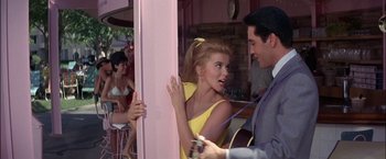 Movie still from “Viva Las Vegas” (1964), directed by George Sidney – A man and a woman are playing a guitar in front of a crowd; Medium shot, Over the shoulder angle