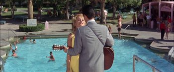 Movie still from “Viva Las Vegas” (1964), directed by George Sidney – A man and a woman standing next to each other in front of a swimming pool; Wide shot, Over the shoulder angle