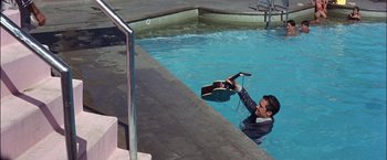 Movie still from “Viva Las Vegas” (1964), directed by George Sidney – A man in a swimming pool holding a guitar; Wide shot, High angle