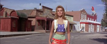 Movie still from “Viva Las Vegas” (1964), directed by George Sidney – A woman standing on the side of the road in front of buildings; Medium shot, Low angle
