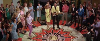 Movie still from “Viva Las Vegas” (1964), directed by George Sidney – A group of people standing in a room; Wide shot, High angle