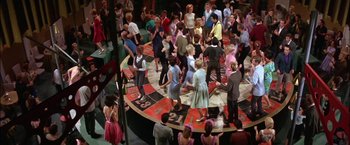 Movie still from “Viva Las Vegas” (1964), directed by George Sidney – A group of people standing around a room; Wide shot, High angle