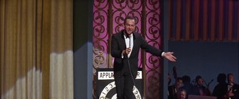 Movie still from “Viva Las Vegas” (1964), directed by George Sidney – A man in a suit and tie holding a microphone; Medium shot, High angle