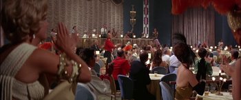 Movie still from “Viva Las Vegas” (1964), directed by George Sidney – A group of people sitting at tables in a room; Wide shot, Over the shoulder angle
