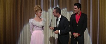 Movie still from “Viva Las Vegas” (1964), directed by George Sidney – A man and a woman are talking to each other while holding microphones in their hands; Medium shot, Low angle