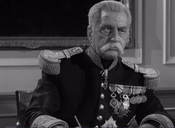 Movie still from “Viva Zapata!” (1952), directed by Elia Kazan – An older man in a military uniform sitting in front of a painting; Medium shot, High angle