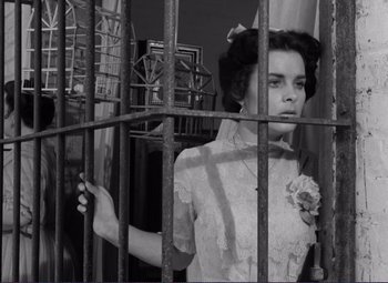 Movie still from “Viva Zapata!” (1952), directed by Elia Kazan – A young woman standing behind a metal fence; Medium shot, Low angle