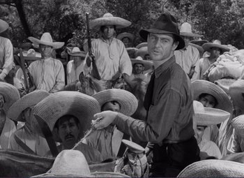 Movie still from “Viva Zapata!” (1952), directed by Elia Kazan – An old photo of a man in a crowd of men wearing hats; Medium shot, Over the shoulder angle
