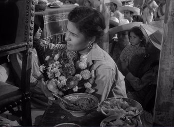 Movie still from “Viva Zapata!” (1952), directed by Elia Kazan – A woman sitting at a table in front of bowls of food; Medium shot, Low angle