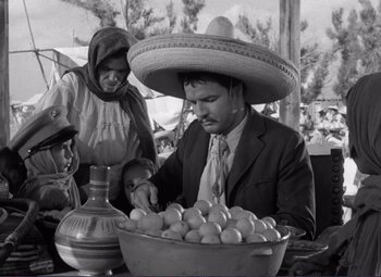 Movie still from “Viva Zapata!” (1952), directed by Elia Kazan – A man wearing a sombrero sitting in front of a bowl of fruit; Medium shot, Low angle