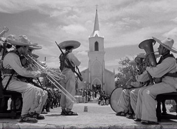 Movie still from “Viva Zapata!” (1952), directed by Elia Kazan – A black and white photo of a group of men playing musical instruments in front of a church; Extreme Wide shot, Low angle